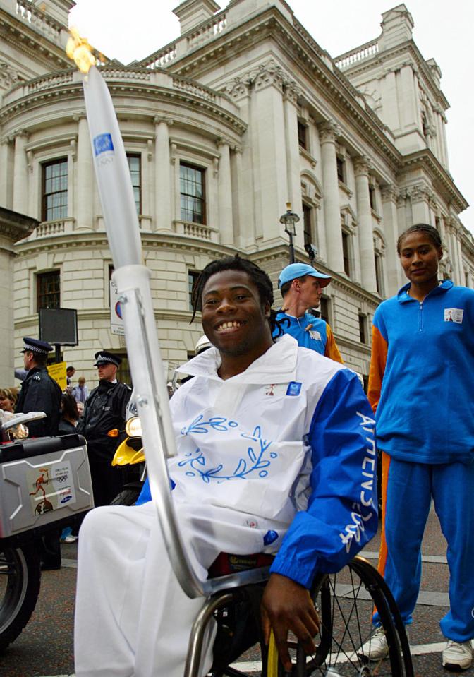 Ade Adepitan, a member of the Great Britain Paralympic basketball team, carries the Olympic torch in London.