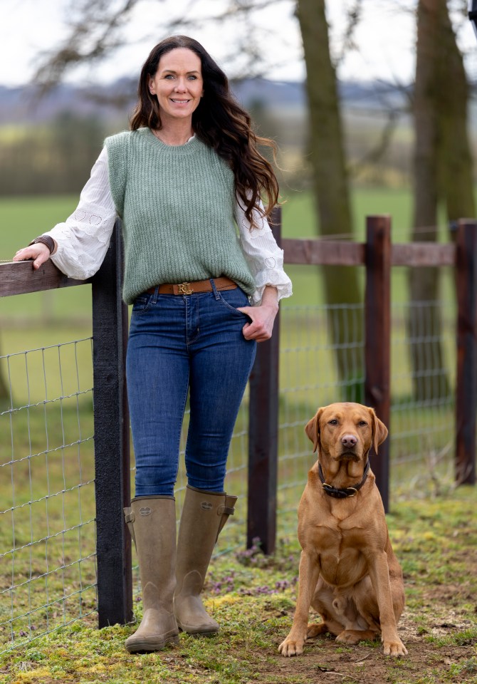 Abby Cohen standing by a fence with her dog.