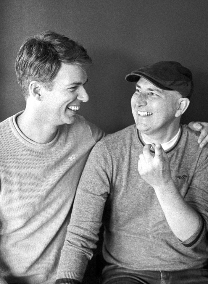 Black and white photo of two smiling men sitting together.