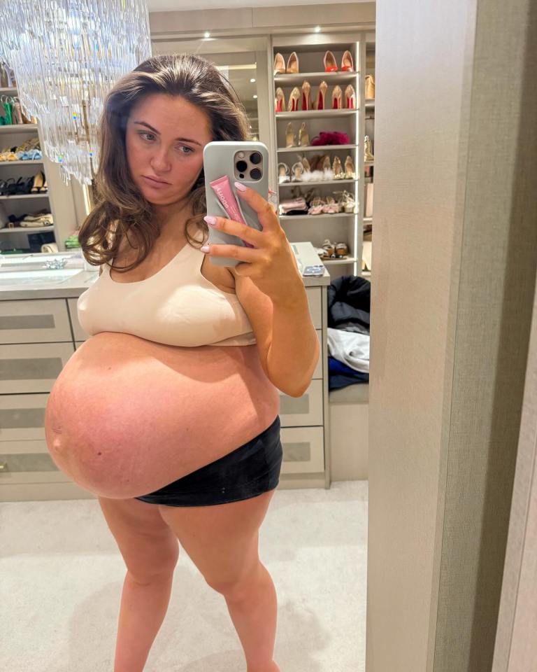 Pregnant woman taking a selfie in front of a mirror.