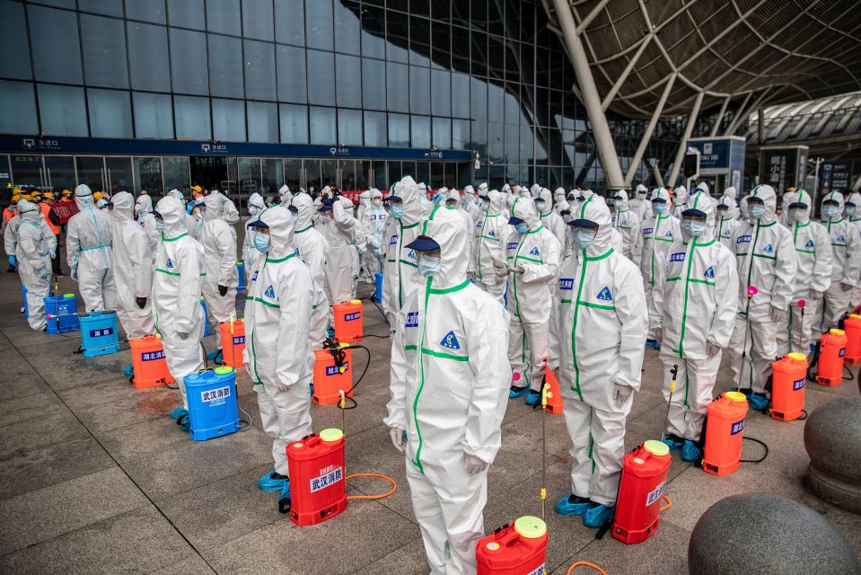 Personnel in protective suits and masks prepare to disinfect Wuhan Railway Station.