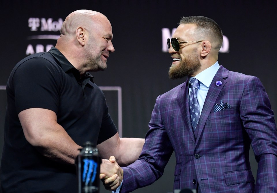 Conor McGregor shaking hands with UFC president Dana White at a press conference.