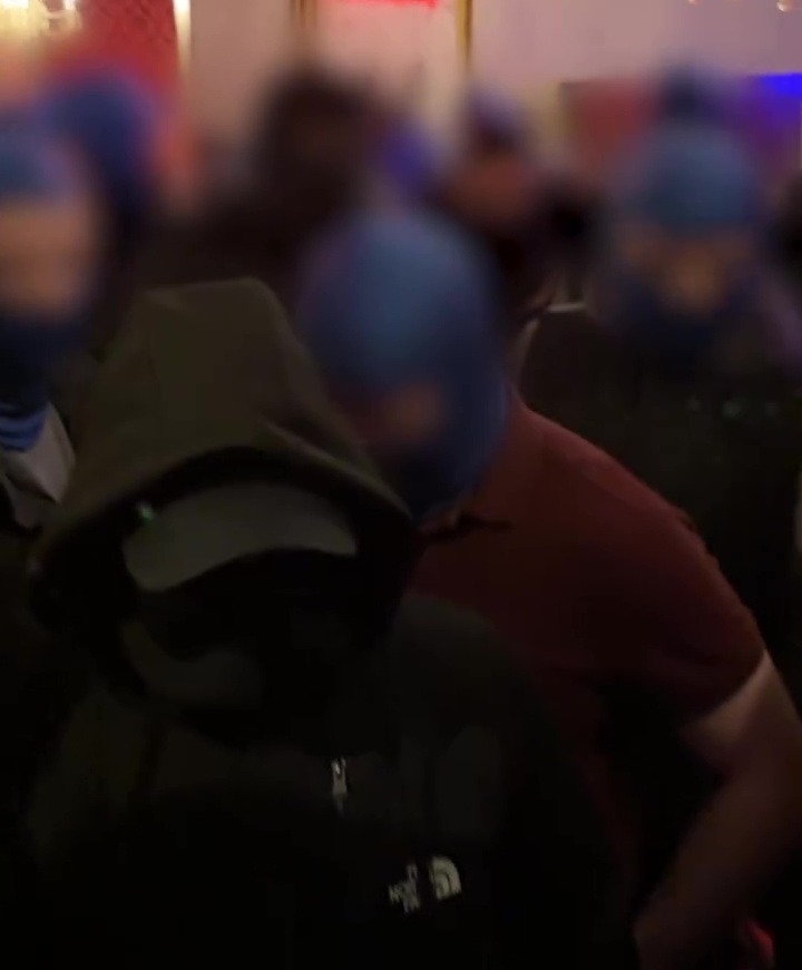 Blurred image of people wearing blue balaclavas.