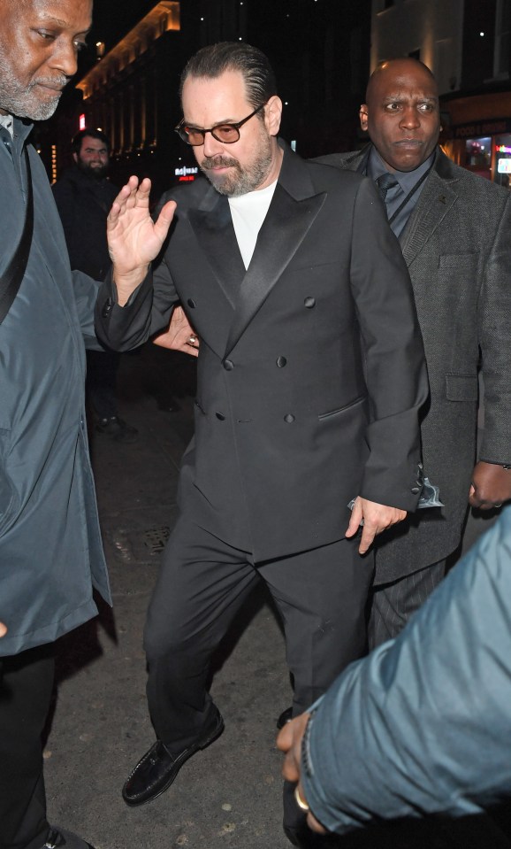 Danny Dyer leaving a party in Soho, London, escorted by a security guard.