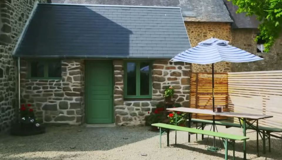 Stone cottage courtyard with picnic table and umbrella.