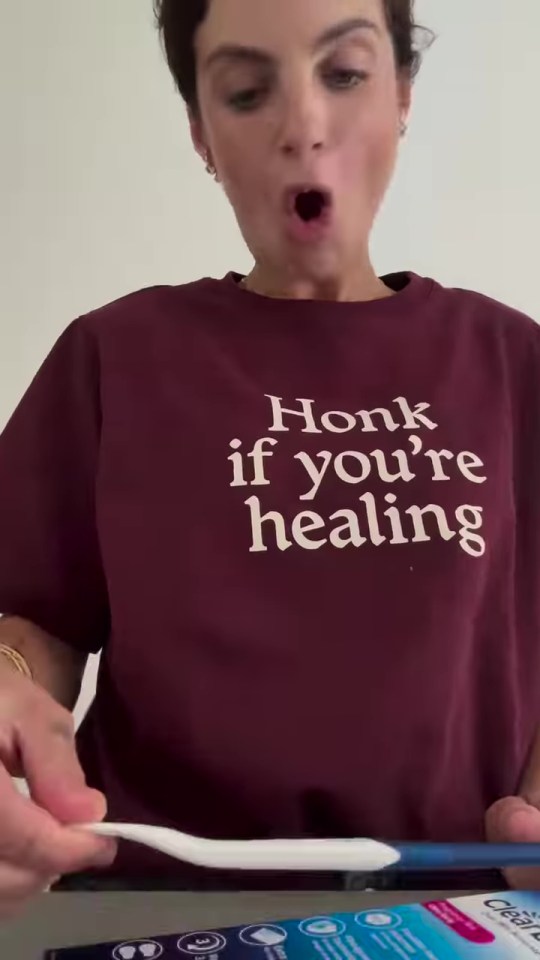 Domenica Calarco holding a tongue scraper while wearing a shirt that says "Honk if you're healing".