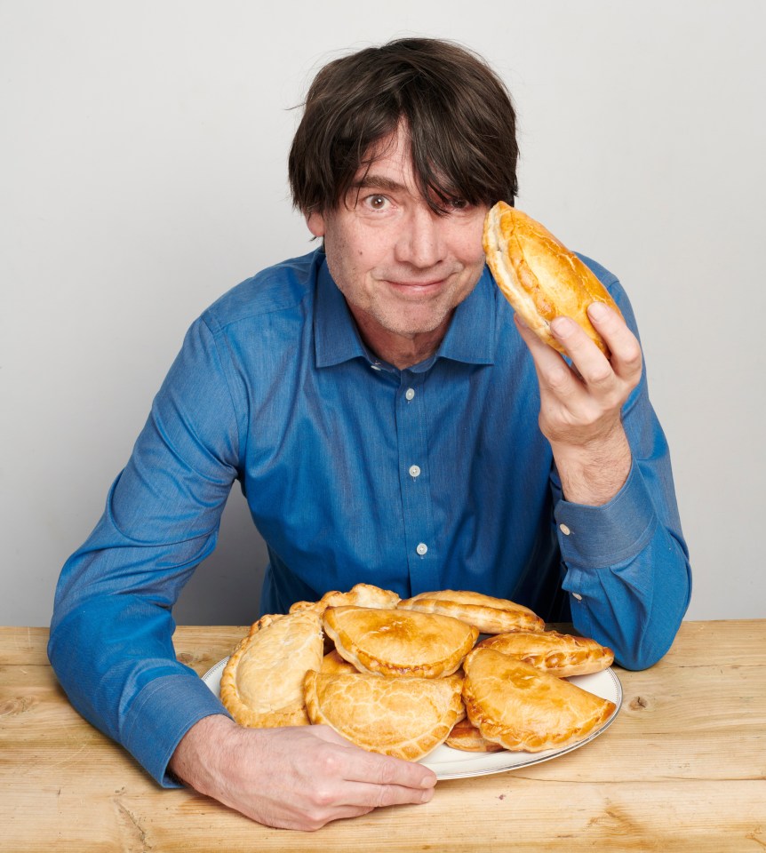 Man holding and surrounded by Cornish pasties.