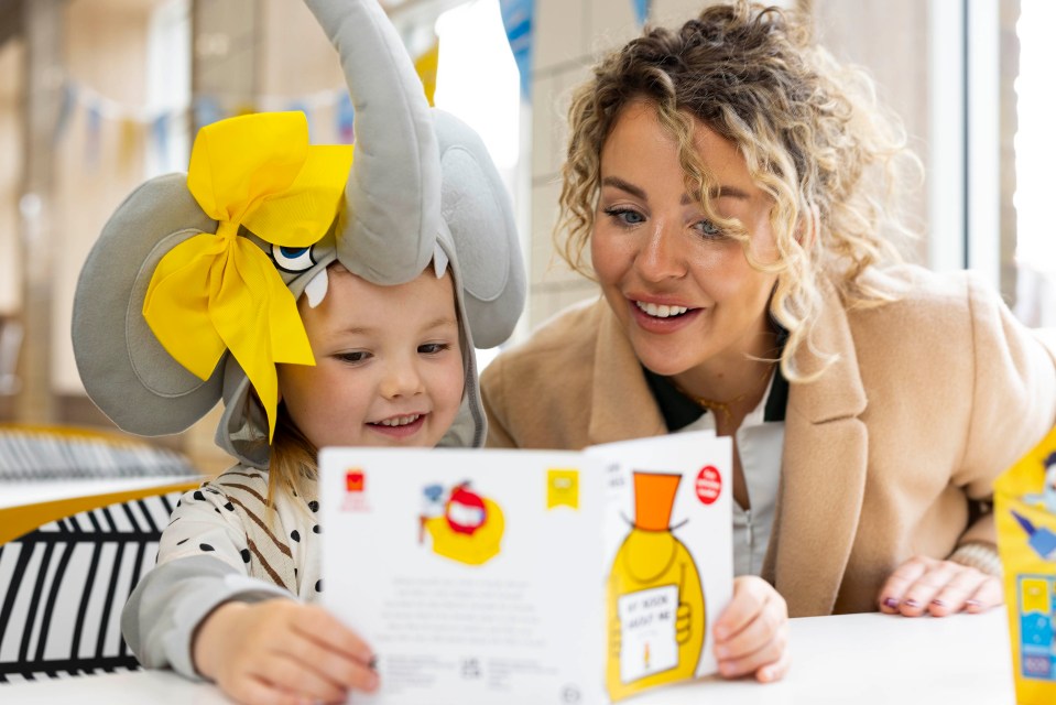 A mother and daughter read a book together.  The daughter is wearing an elephant costume.