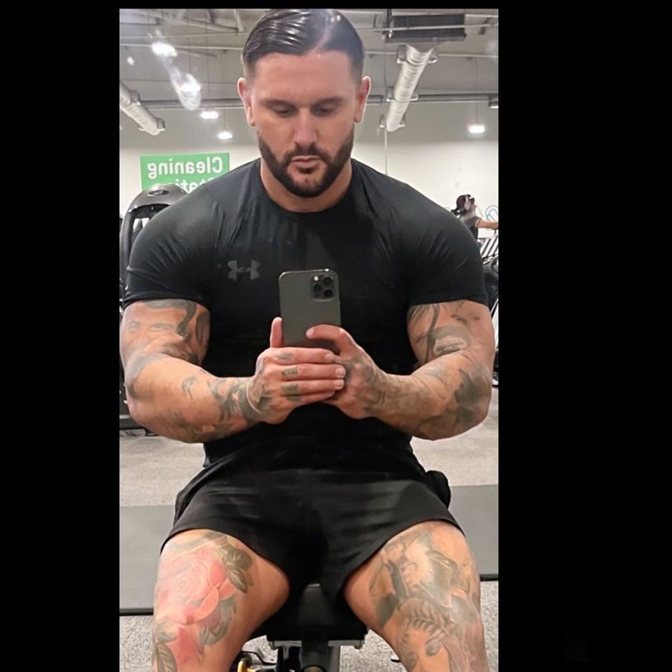 Man with tattoos looking at his phone at the gym.