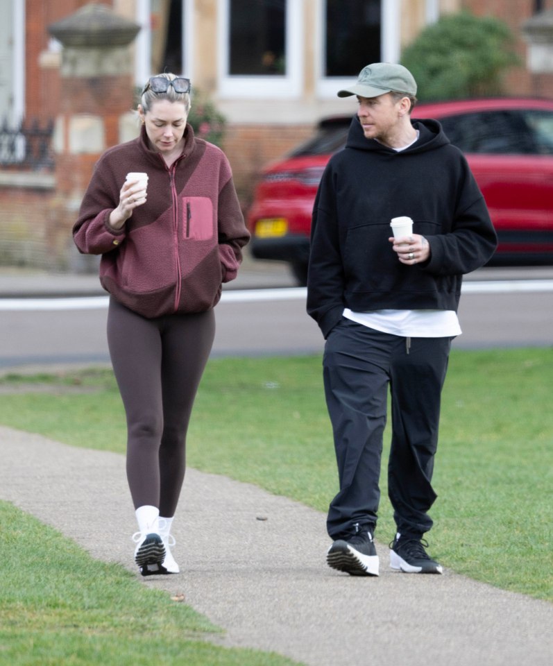 Danny and Georgia Jones walking and holding coffees.