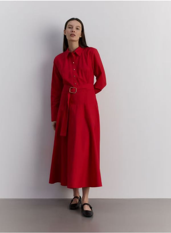 Woman in a red belted shirt dress and black shoes.