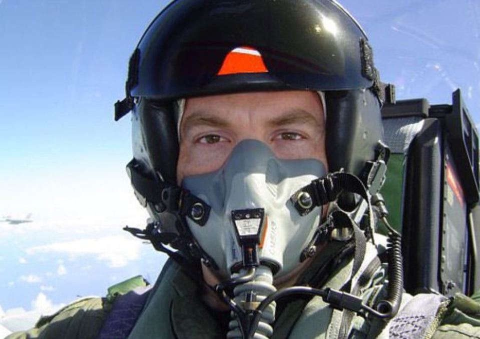 Close-up of a Navy pilot wearing a helmet and oxygen mask.