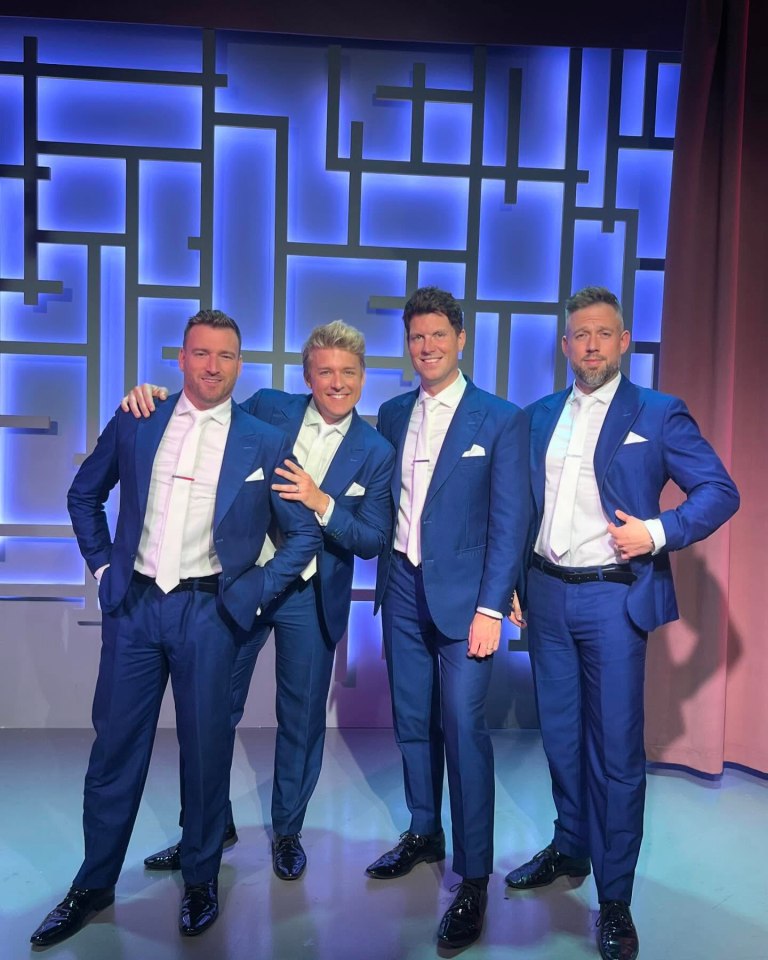 Four men in blue suits posing together.