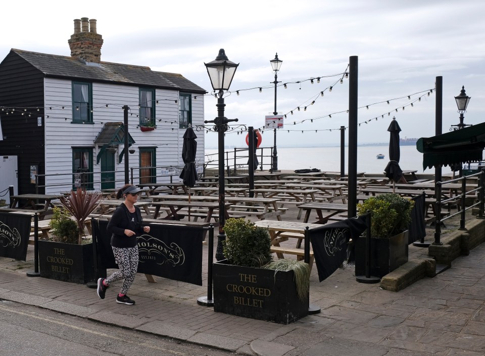 Woman jogging past The Crooked Billet pub in Leigh-on-Sea.