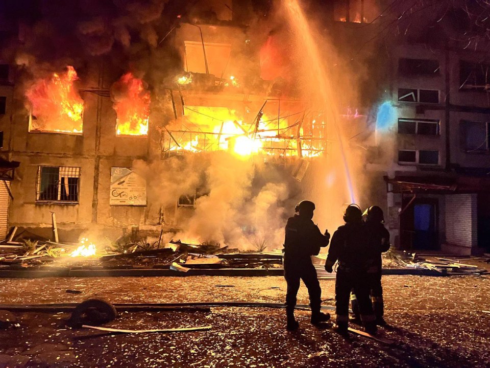 Firefighters battling a large building fire at night.