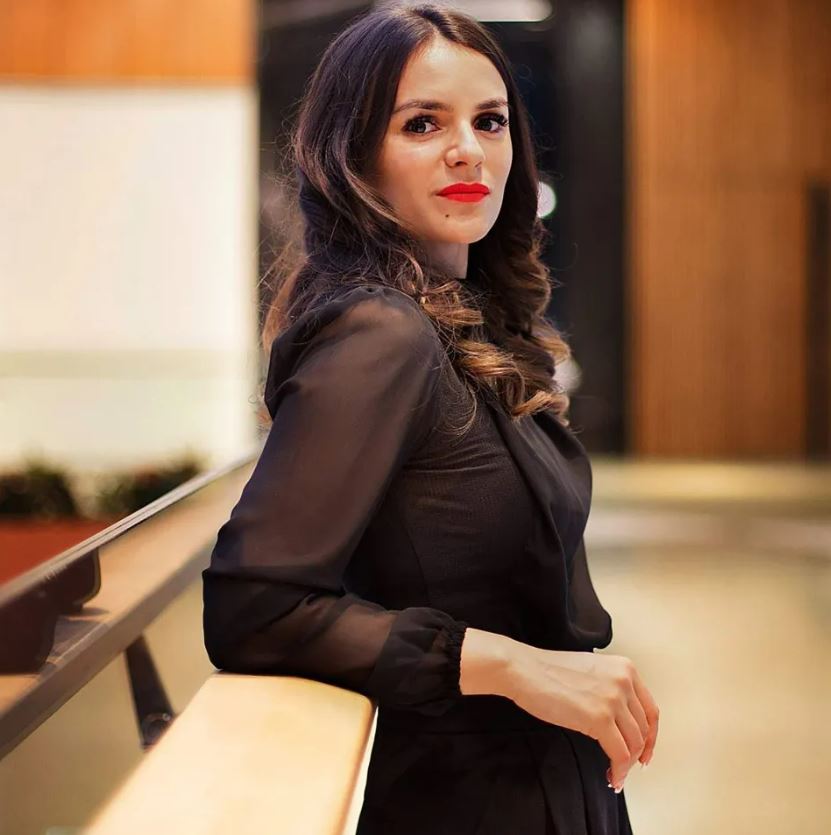 Woman in black shirt leaning on railing.