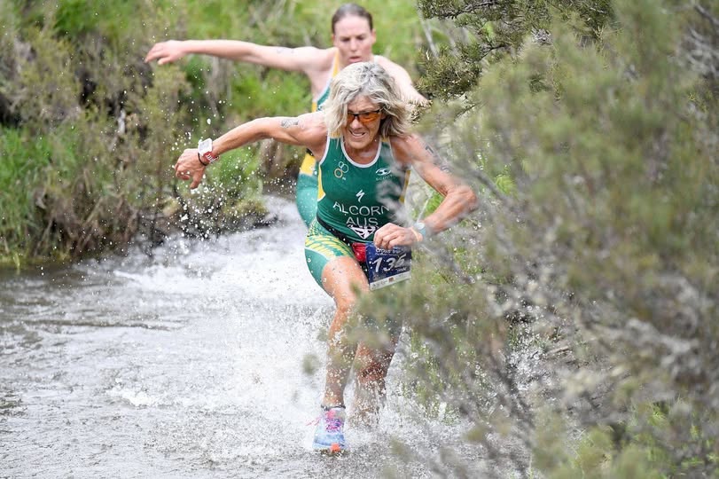 Triathlete running through water.