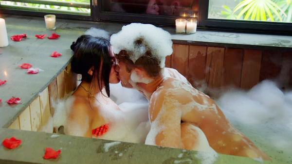 Couple kissing in a bubble bath.