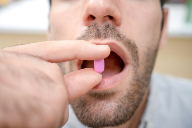 Man taking a pink pill.