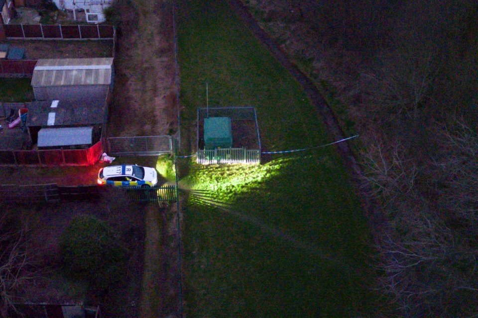 Aerial view of a crime scene at night, with police car and crime scene tape.