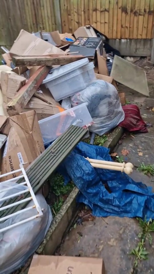 Pile of discarded rubbish including cardboard boxes, plastic containers, and wood.