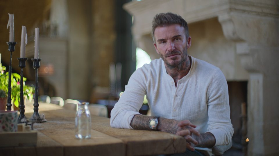 David Beckham sitting at a wooden table.