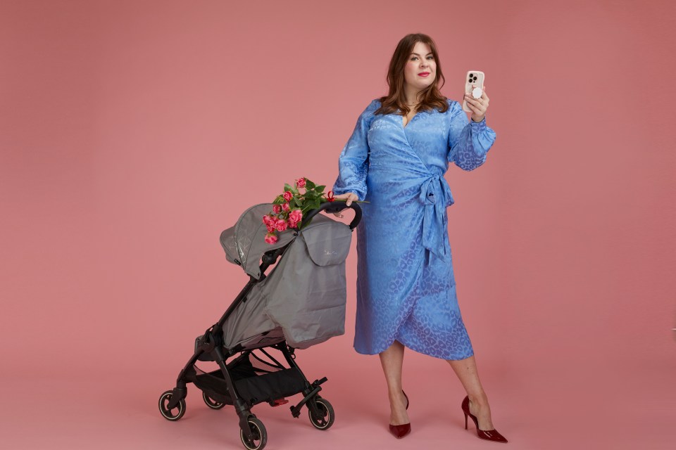 Woman in blue dress holding phone and standing next to stroller with roses.