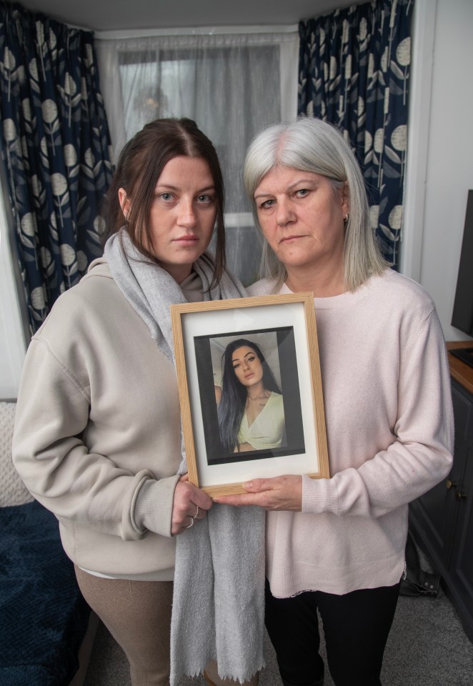 Two sisters holding a framed photo of their deceased sister.