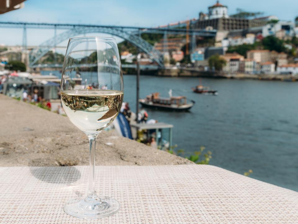 White wine glass overlooking a river and bridge in Porto, Portugal.