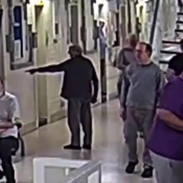 A man in prison gestures angrily toward another inmate.