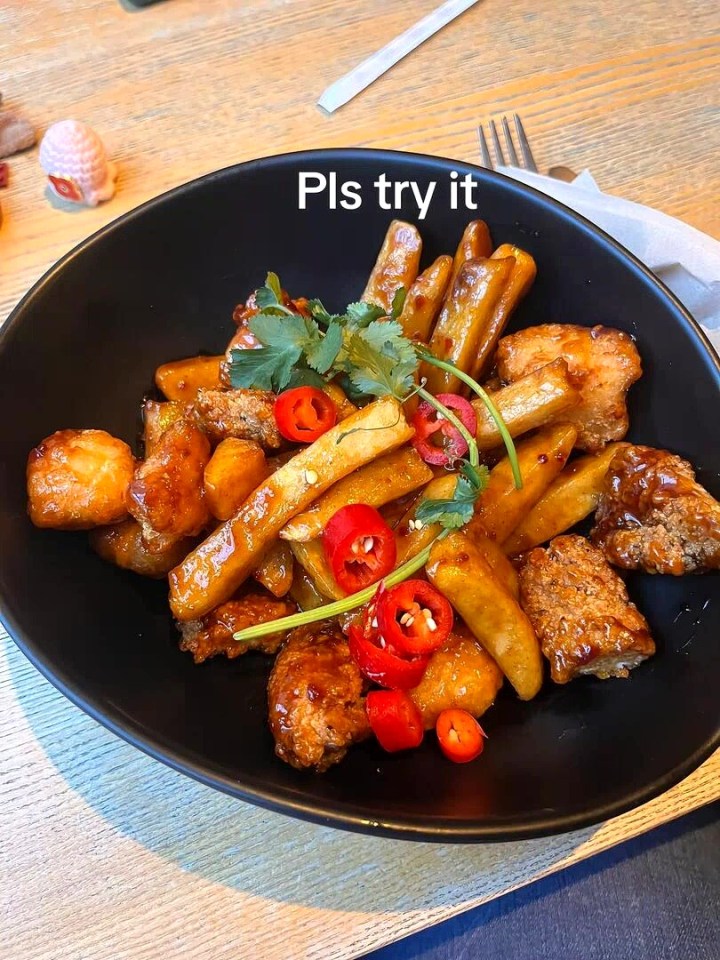 Dish of fries and breaded chicken with chili peppers and cilantro.